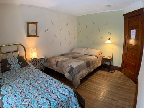 a bedroom with two beds and a lamp and a door at Wanderfalls Guesthouse & Hostel in Niagara Falls