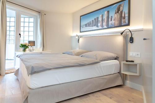 um quarto com uma grande cama branca com uma fotografia na parede em Poseidon em Westerland