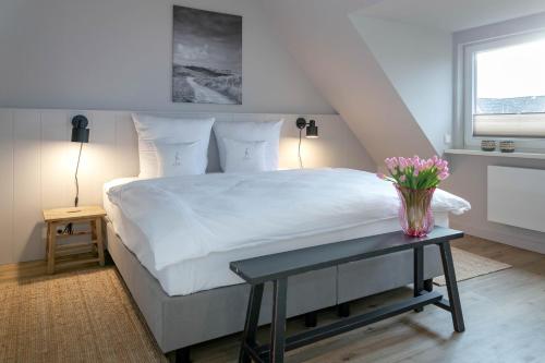 ein Schlafzimmer mit einem Bett mit einer Vase aus Blumen auf dem Tisch in der Unterkunft Seetiid in Westerland