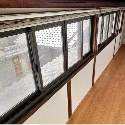 a row of windows in a room with a wooden floor at 古民家民泊かえるて in Kashihara