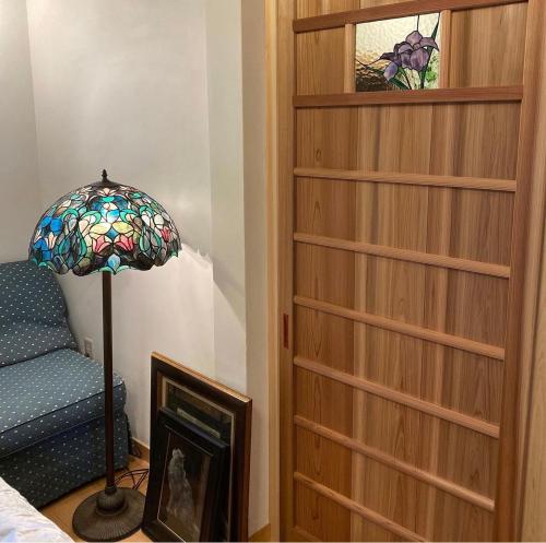 a bedroom with a book shelf and a lamp next to a bed at 古民家民泊かえるて in Kashihara