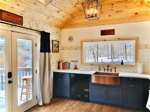 uma cozinha com armários azuis, um lavatório e uma janela em Charming 120-year-old farmhouse by the creek. em Starlight