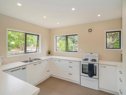 a kitchen with white cabinets and a stove top oven at Seas the Day - Matarangi Holiday Home in Matarangi