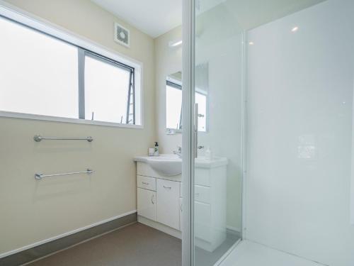 a white bathroom with a sink and a shower at Seas the Day - Matarangi Holiday Home in Matarangi