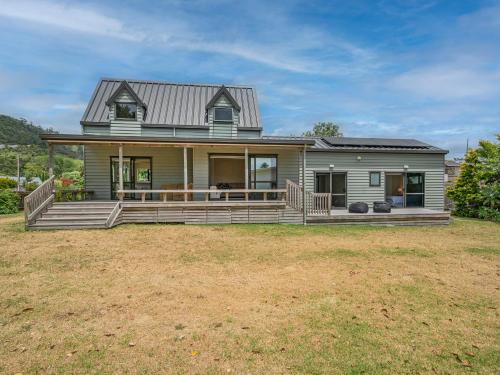 a large house with a large porch on a yard at Seas the Day - Matarangi Holiday Home in Matarangi