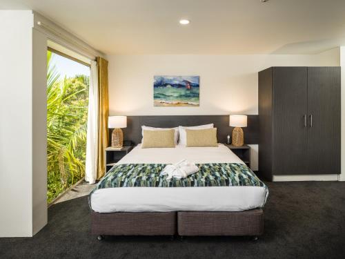 a bedroom with a large bed and a large window at Carnmore Hotel Takapuna in Auckland