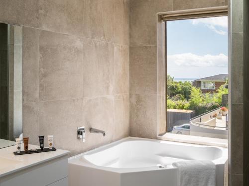 a bath tub in a bathroom with a window at Carnmore Hotel Takapuna in Auckland