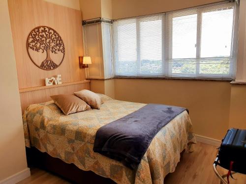 um quarto com uma cama com uma imagem de árvore na parede em Apto Centro de Gramado (2D c/Piscina Térmica) em Gramado