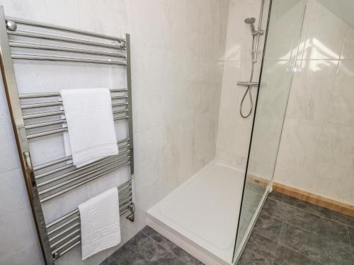 a bathroom with a glass shower stall with towels at Lea Farm House in Kidderminster