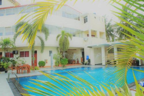 a hotel with a swimming pool in front of a building at The Ocean Pearl Hotel Negombo in Negombo