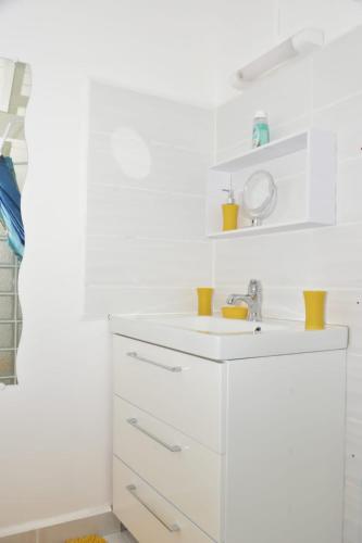 a white bathroom with a sink and a mirror at Studio Hibiscus in Petit-Bourg