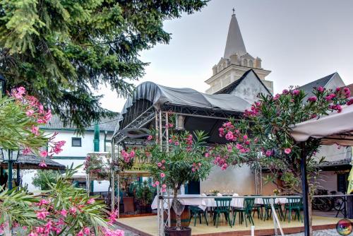 a restaurant with tables and flowers in front of a church at Turmhof Breitenbrunn in Breitenbrunn