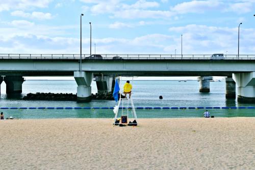 a man on a ladder on the beach near a bridge at TOMMY CONDOMINIUM WAKASA 601 in Naha