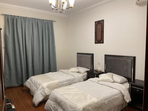 a hotel room with two beds and a chandelier at sun sets for family only in Durat  Alarous
