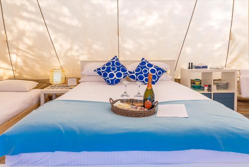 a bed with a basket of fruit and a bottle of wine at Busselton Villas and Glamping Village in Busselton