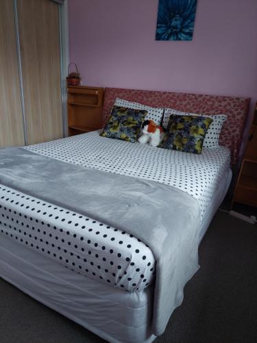 a bed with a teddy bear sitting on top of it at Wendy's Holiday Home in Auckland