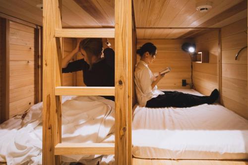 zwei Personen, die in einem Etagenbett auf Betten sitzen in der Unterkunft FOLK FOLK Hostel, Cafe & Bar in Ise