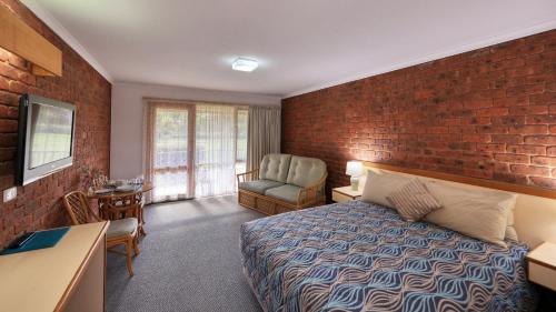 a hotel room with a bed and a brick wall at Tooleybuc Club Motor Inn in Tooleybuc