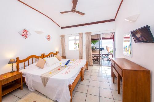 a bedroom with two beds and a balcony at Anse Soleil Beachcomber Hotel and Self Catering in Baie Lazare Mahé