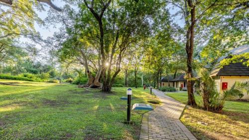 a brick path through a park with trees and a building at Sanbonani Hotel in Hazyview