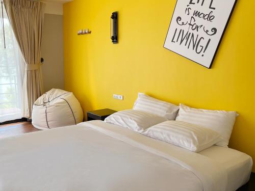 a bedroom with a white bed with a yellow wall at Blue Orchid Beach Krabi - SHA Certified in Ao Nam Mao