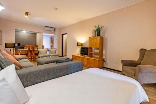 a living room with a bed and a couch and chairs at Sanbonani Hotel in Hazyview