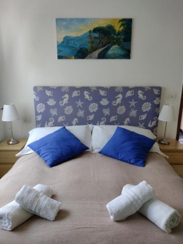 a bed with blue pillows and two towels on it at Soleluna in Capri