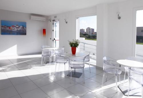 a white room with white tables and chairs and windows at Brezza Di Grecale in Trapani