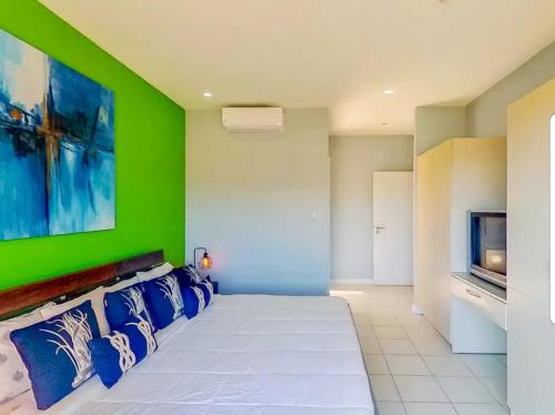 1 dormitorio con cama blanca y pared verde en The Best Ocean and Mountain views in the city, en Jacó