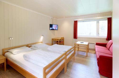 1 dormitorio con 1 cama y 1 sofá rojo en Skjåk Turistheim, en Skjåk