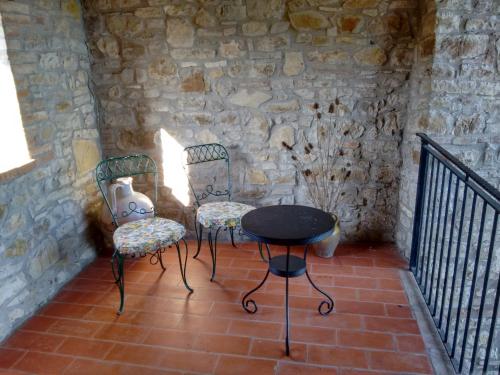 two chairs and a table in a room with a stone wall at Agriturismo Casa Greppo in San Venanzo