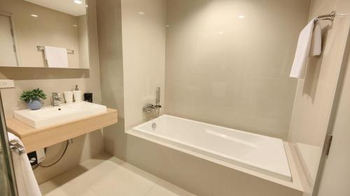 La salle de bains est pourvue d'une baignoire blanche et d'un lavabo. dans l'établissement Hill & Valley Khaoyai by Nancy, à Ban Huai Sok Noi