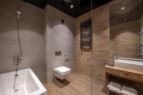 a bathroom with a tub and a toilet and a sink at Bristol Hotel and Spa Bakuriani in Bakuriani
