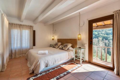 a bedroom with a bed and a large window at Mas del Gall - Casa Nova in Tordera