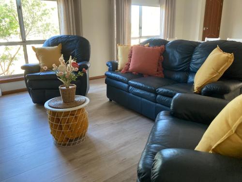 a living room with two black leather couches and a table at CandE on Buller in Kingscote