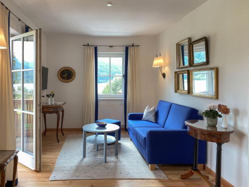 a living room with a blue couch and a table at Seehotel Enzian in Weissensee