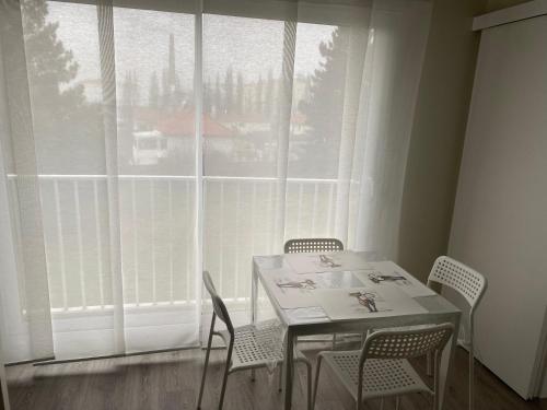 einen Tisch und Stühle in einem Zimmer mit einem großen Fenster in der Unterkunft Appartement Parc de Fresnoy in Roye