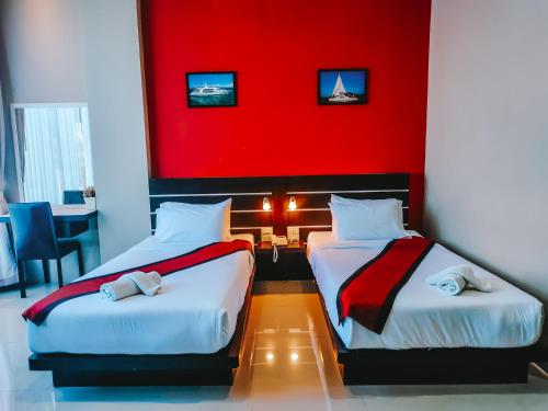 two beds in a room with a red wall at The Harbour Front Hotel in Suratthani