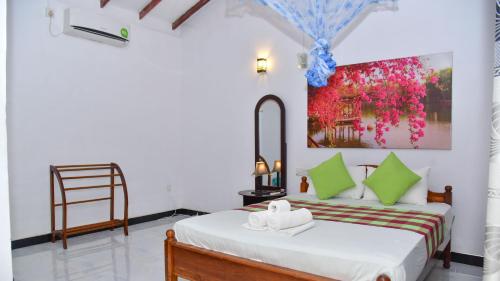 a bedroom with a bed and a painting on the wall at Sayare Inn in Dambulla