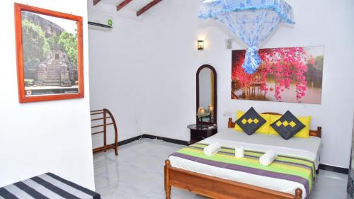 a bedroom with a bed and a painting on the wall at Sayare Inn in Dambulla