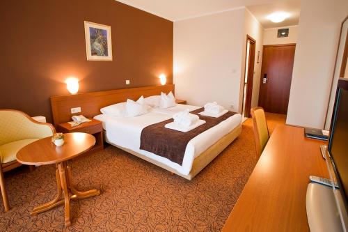 a hotel room with two beds and a television at Spa & Wellness Hotel Pinia in Malinska