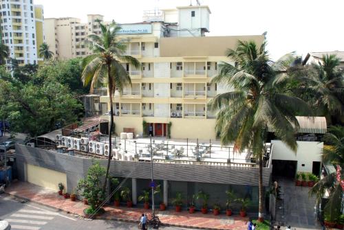 a building with palm trees in front of it at Hotel Metro Palace Bandra in Mumbai