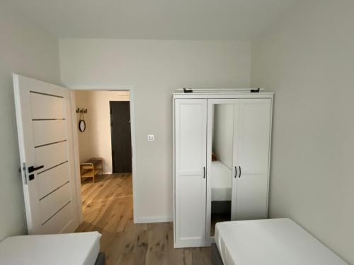 um quarto branco com 2 camas e um closet em Apartment Insat II em Szczecin