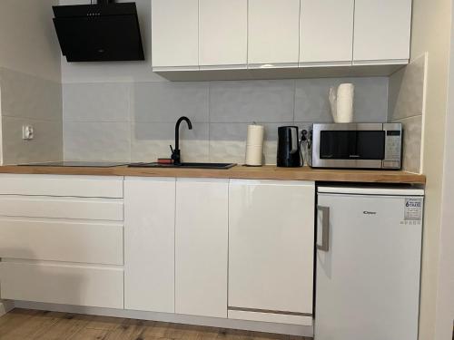 a white kitchen with a microwave and a refrigerator at Apartment Insat II in Szczecin