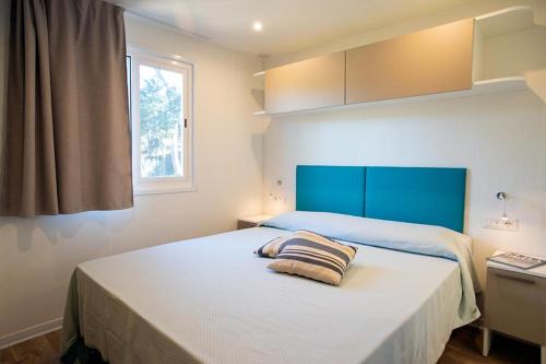 a bedroom with a bed with a blue headboard and a window at Camping Europa in Capoliveri