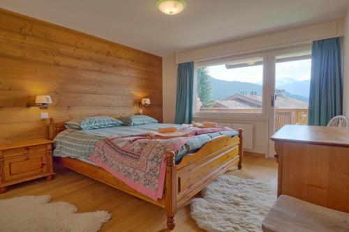 ein Schlafzimmer mit einem Bett und einem großen Fenster in der Unterkunft Levrauts 321 in Verbier