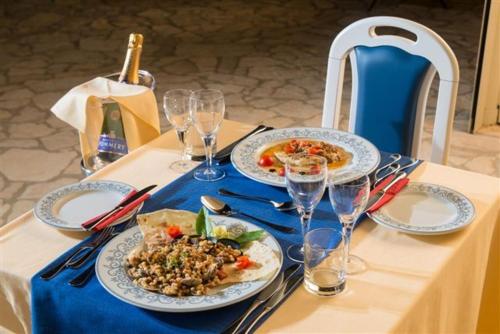 a table with plates of food and wine glasses at Hotel Ristorante Il Vascello in Costa Rei