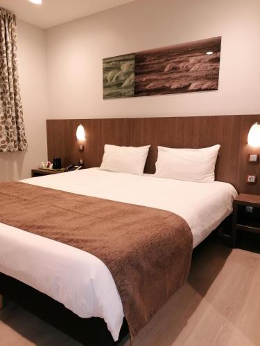 a bedroom with a large bed with white sheets at The Originals City, L'Haut' Aile, Coquelles-Calais Tunnel s/Manche L'HAUTAILE in Coquelles