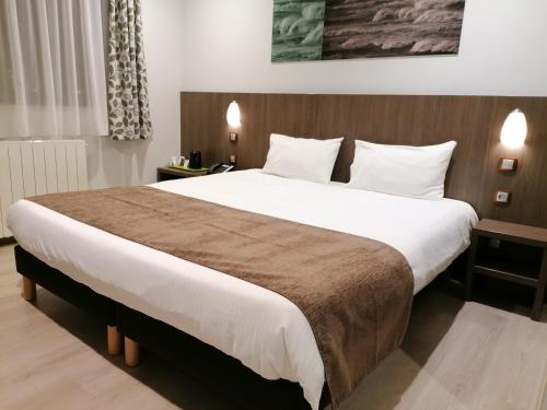 a bedroom with a large bed with white sheets at The Originals City, L'Haut' Aile, Coquelles-Calais Tunnel s/Manche L'HAUTAILE in Coquelles