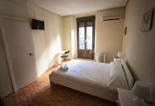 1 dormitorio con cama blanca y ventana en Hostal Los Perales, en Madrid